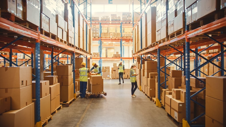 Workers in safety gear in a warehouse full of cardboard boxes