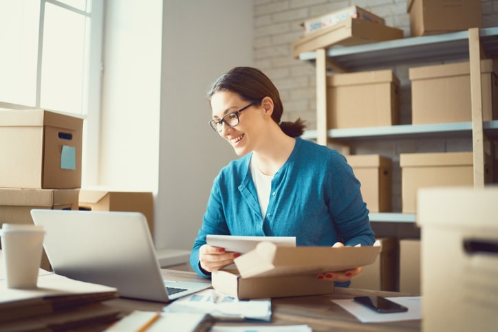 Business owner smiles while packing orders.