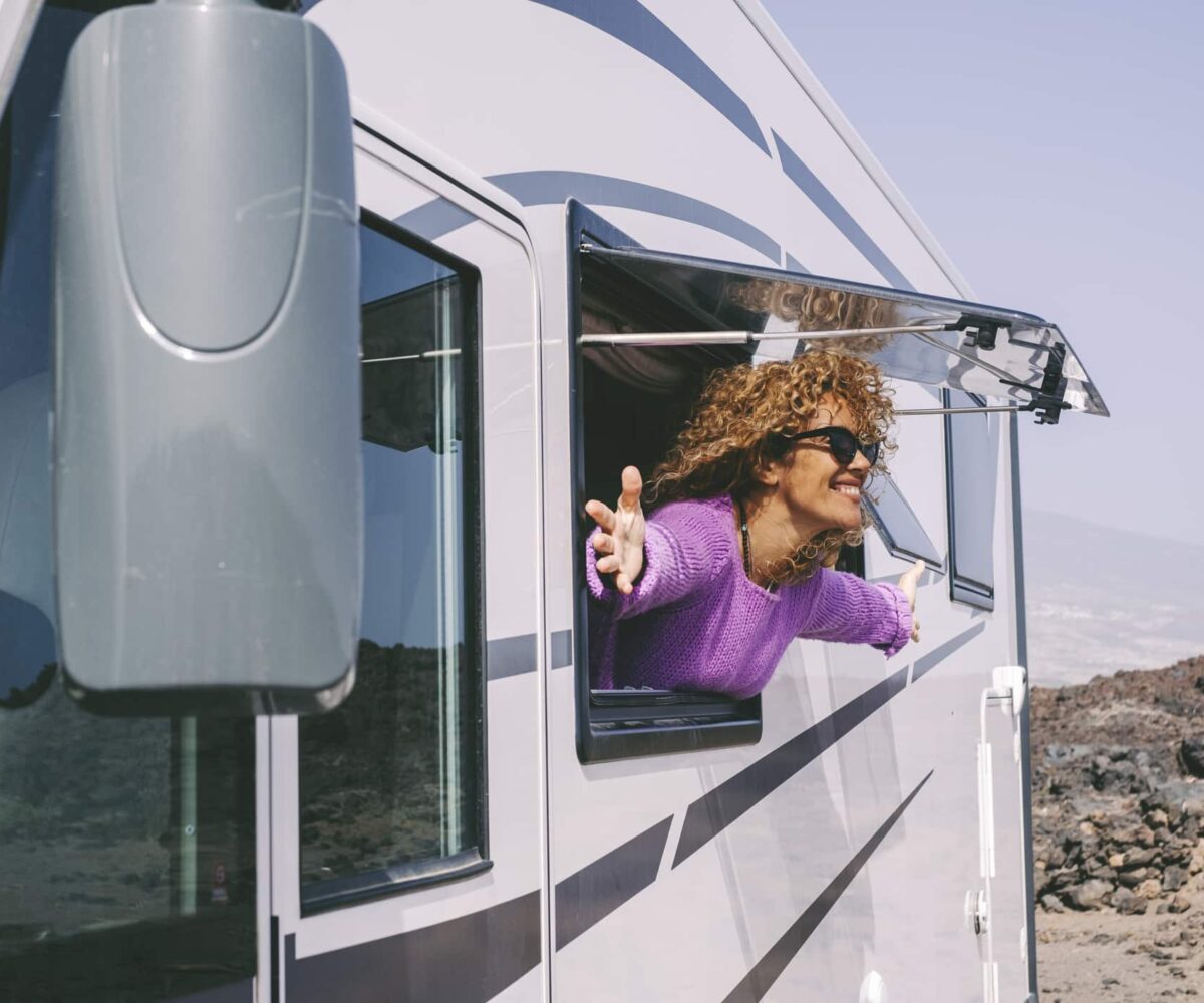 A traveler smiles while looking out of the window of an RV