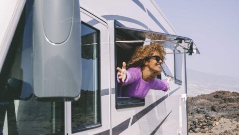 A traveler smiles while looking out of the window of an RV