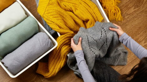 Woman folding wool sweater to restore order to her space.