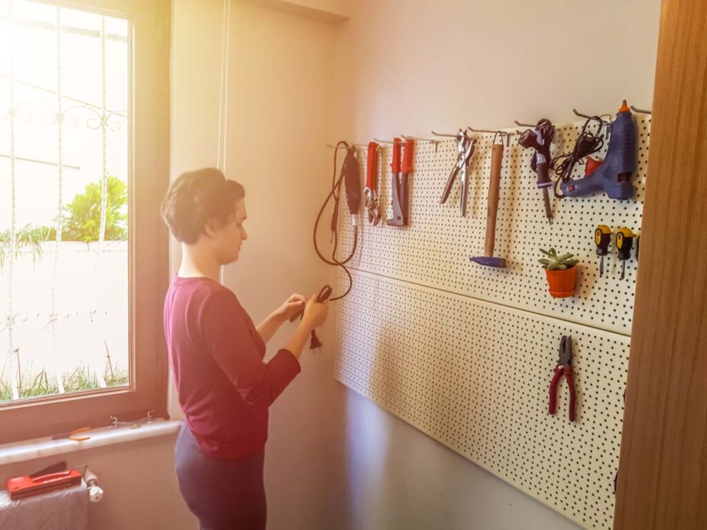 Picture of woman organizing tools on pegboard.