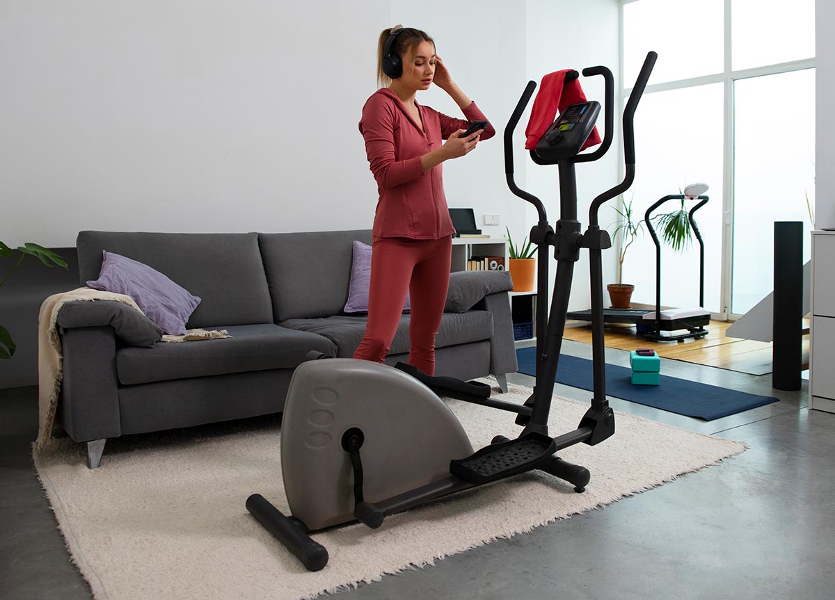 woman about to exercise on elliptical machine at home.